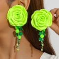 Close-up of neon green camellia fabric earrings with beaded fringe tassels on model - Cyan