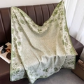 Detailed view of a green floral silk square scarf elegantly draped on a leather sofa - Green (XW-175)