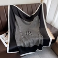Macro view of geometric striped silk scarf draped on a leather sofa showing satin texture - 90*90cm / Black