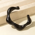 Close-up of matte black irregular wave-shaped acrylic bracelet on beige velvet stand - Fluid Wave Style (31204) / Matte Black