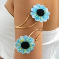 Gedetailleerde close-up van een gouden bovenarmband met blauwe stoffen bloemen op een model - Hemelsblauw