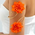 Detail eines goldenen Spiral-Armreifs mit großen orangefarbenen Stoffblumen am Arm - Orange