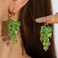 Close-up of bright green crystal grape bunch earrings with gold hooks on a model - Green