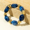 Detail of blue marble resin beads and golden metallic spacers on a yellow display stand - Dark Blue Marble Pattern Bead Bracelet (31597)