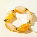 Macro view of amber-toned resin beads with gold metal spacers on a stone plate - Amber Yellow Large Grain Pebble Bracelet (31599)