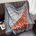 Retro paisley silk square scarf in navy blue and orange displayed on leather surface - Orange