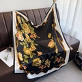 Floral print satin square scarf with yellow roses draped over a luxury leather sofa - Black (DM-40)