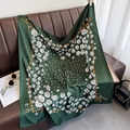 Detail of dark green 90cm square silk scarf with floral prints on a leather sofa - Green