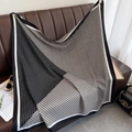 Detail of luxury silk square scarf with geometric pattern on brown leather sofa - Black