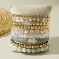 Detailansicht der mehrlagigen Boho-Armbänder mit CCB-Perlen und Steinen auf einem Kissen - Gold Weiß Grau Gemischtes Material Strass Stern 9-teiliges Set (31097-bra-col-EP)