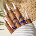 Close-up of five gold rings set with blue crystals and butterfly floral motifs - Blue