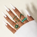 Detail of five-piece gold ring set with green gemstones on a female model's hand - Green