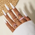 Close-up of gold finish ring set featuring pink crystals and butterfly designs - Pink
