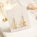 Détail de boucles d'oreilles étoile de mer en acrylique crème sur fond de sable - Style Étoile de Mer Texturée Beige (29368-2)