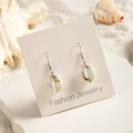 Close-up of beach style cowrie shell earrings on sand background with silver hooks - White Brown Spotted Cowrie Shell Style (29368-7)