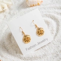 Détails de boucles d'oreilles coquillage dorées sur du sable blanc avec coquilles - Style Organique Texturé Irrégulier (29421-7)