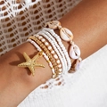 Detail of bohemian starfish pendant with layered shell beads and gold beaded bracelets - Gold White