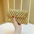 Detailed close-up of champagne gold evening bag with inlaid pearls and sparkling rhinestones - Gold