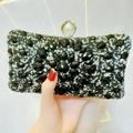 Close-up of black beaded evening clutch with silver sequins and pearl clasp decoration - Black