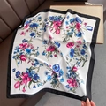Detail eines Seidenschals mit Blumenmuster und schwarzem Rand auf einem Ledersofa - Schwarzer Rand Blumen