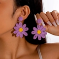 Close-up of model wearing purple raffia woven flower earrings with yellow stamen - Purple