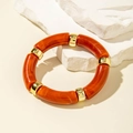 Close-up of orange marble acrylic tube bracelet with elegant gold metallic spacers - Curved Tube Style (29808-A) / Orange Red