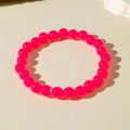 Macro di un braccialetto di perle acriliche rosa acceso su sfondo minimalista - Rosso Rosa