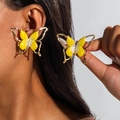 Gros plan d'une boucle d'oreille papillon jaune avec cadre doré porté par un modèle - Grand Jaune (29991-ear-yellow)