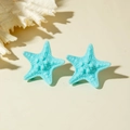 Detail of blue starfish resin earrings with realistic texture on beach style background - Blue