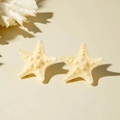 Macro shot of realistic starfish stud earrings featuring detailed sandy beach textures - Beige