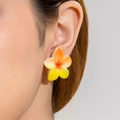 Detailed view of yellow and orange plumeria flower earring on a model ear - Orange Yellow Gradient