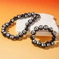 Detail of gothic black skull beads necklace and bracelet set on stone pedestals - Black Skeleton Necklace Bracelet Set (30076-BN-black-set)