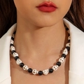 Close-up of gothic black beaded necklace with white skull charms worn on a model's neck - Black White Skeleton Necklace (30440-nek-bw)