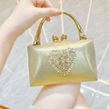 Makro-Detail der goldenen Abendtasche mit Herz-Strasssteinen und Bambus-Griff - Gold