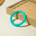 Detail of vibrant teal segment stretch bracelet on linen jewelry tray with natural lighting - Cyan