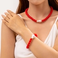 Dettaglio set gioielli con perle rosse e perla barocca su modella femminile - Set Collana e Bracciale / Rosso
