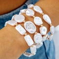 Primo piano di un set di quattro braccialetti di perle con perline dorate al polso - Set da 4 Pezzi Stile Perline Irregolari (30849-bra-white-EP)