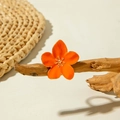 Macro detail of orange enamel flower ring with golden metallic center on wood branch - Orange Five-petal Flower