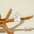 Detailed view of a white enamel flower ring on a natural wood branch with warm shadows - White Flower (DFC128WH)