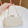 Close-up of pleated evening bag with pearl handle and golden bow clasp - Apricot With Pearl Chain