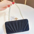 Detail of pleated black evening clutch featuring pearl handle and gold bow clasp - Black With Pearl Chain