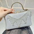 Clutch da sera argento con frange di strass e chiusura a fiocco dorato tenuta in mano - Argento