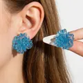 Detail of blue glitter flower stud earrings with transparent resin on female ear - Blue Glitter Transparent Flower Stud Earrings (5962-ear-blue-2)
