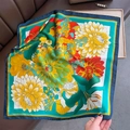 Detailansicht eines hochwertigen Seidenquadrats mit lebhaften Blumenmustern und Satinstruktur - Grün / 70x70cm