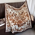Detail view of large square scarf with brown butterfly print on a vintage leather sofa - Coffee