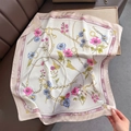 Dettaglio di un foulard di seta satinata con stampa floreale e catene dorate eleganti - Rosa