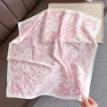 Detail of pink floral silk scarf on a brown leather sofa with decorative pearls - Pink