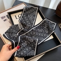 Detail view of black and white paisley skinny silk scarf tied as a luxury bag accessory - Paisley Style / Black