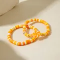 Détail de deux bracelets bohèmes en perles Heishi avec pendentif fleur orange et perles dorées - Ensemble Orange (29909-bra-orange)