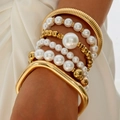 Detail of layered gold bangles and assorted pearl beaded bracelets on a model's wrist - Fashion Pearl Metal Irregular Bangle Group (30275-bra-G white-EP)